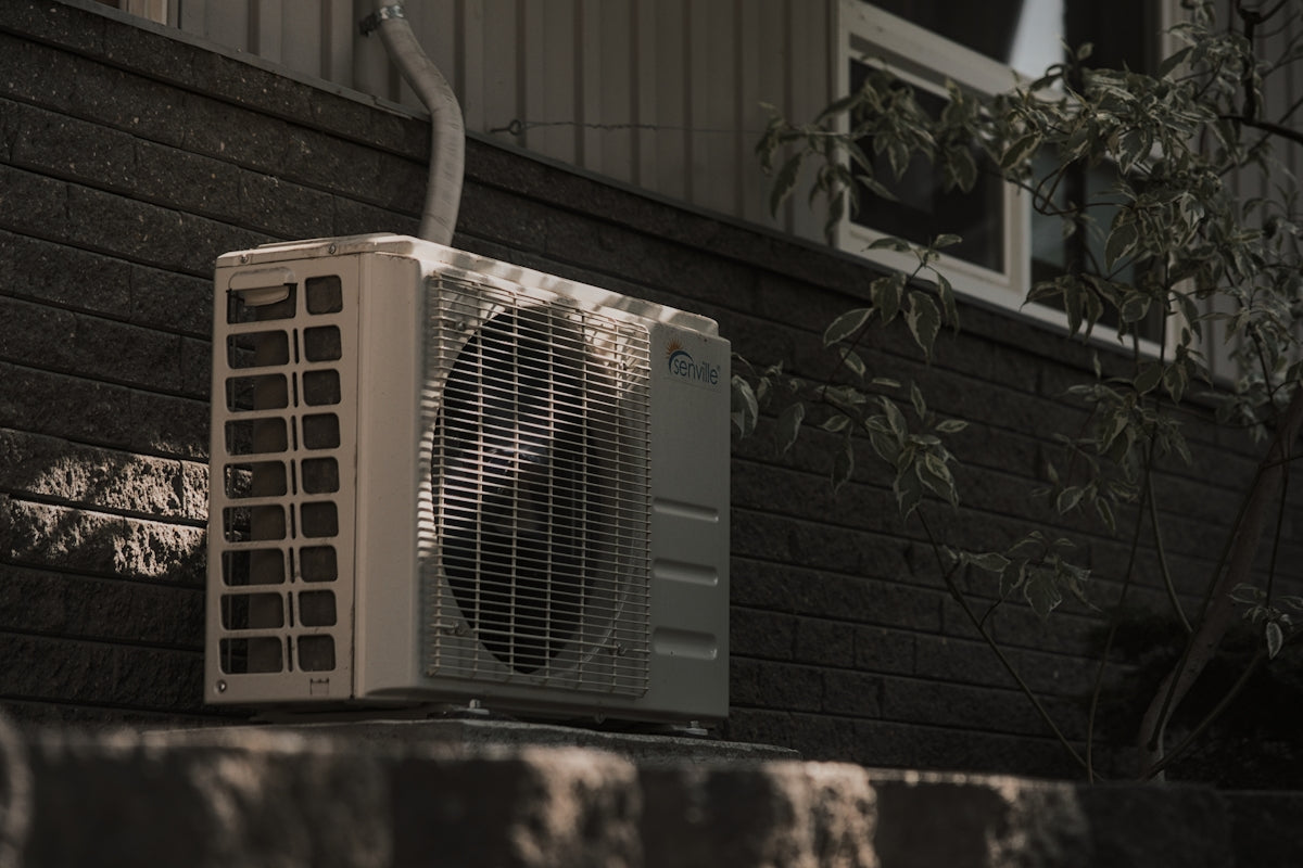 a white air conditioner sitting on top of a brick wall